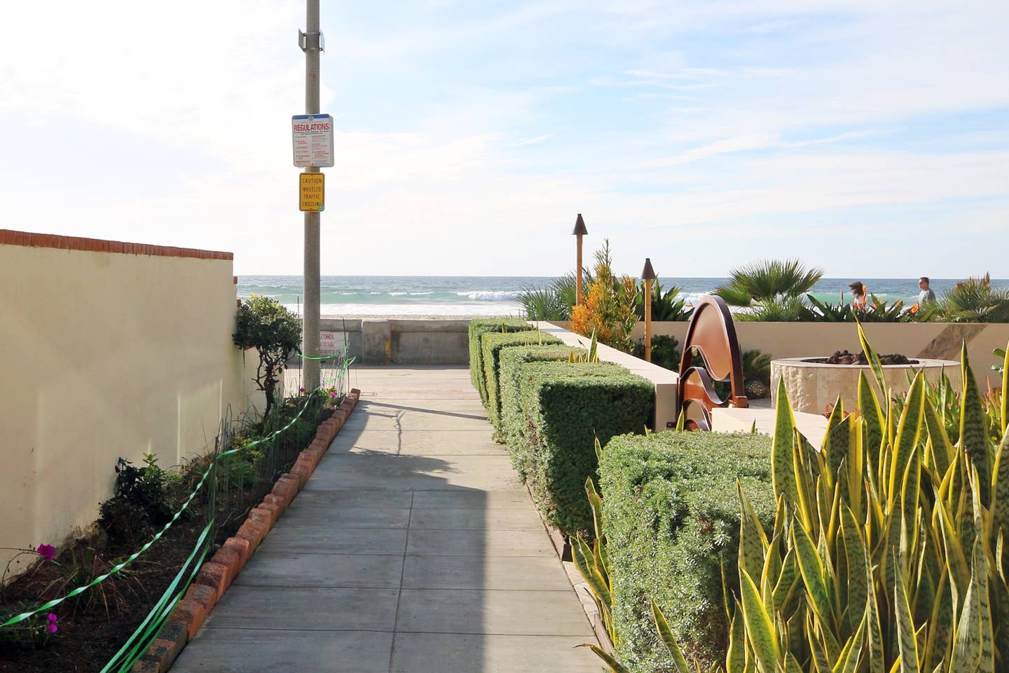 A walkway leading to the beach with a no parking sign