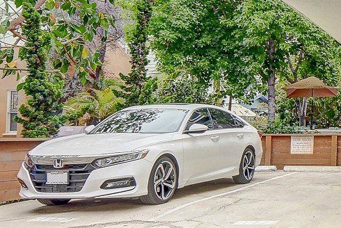 A white honda accord is parked in a parking lot.