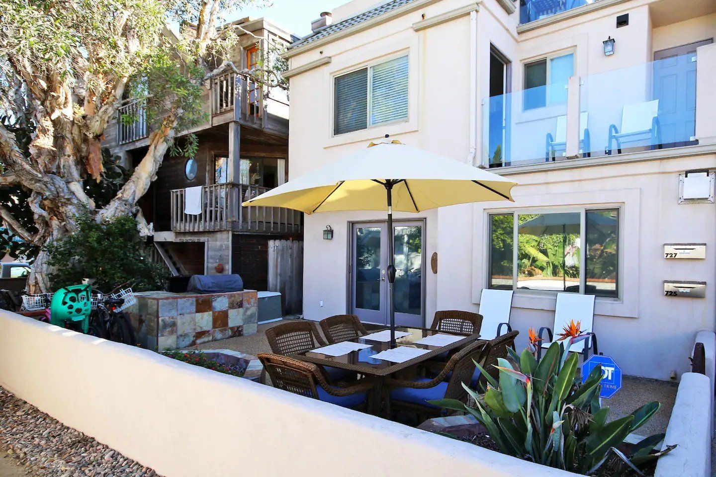 a house with a table and chairs and an umbrella in front of it