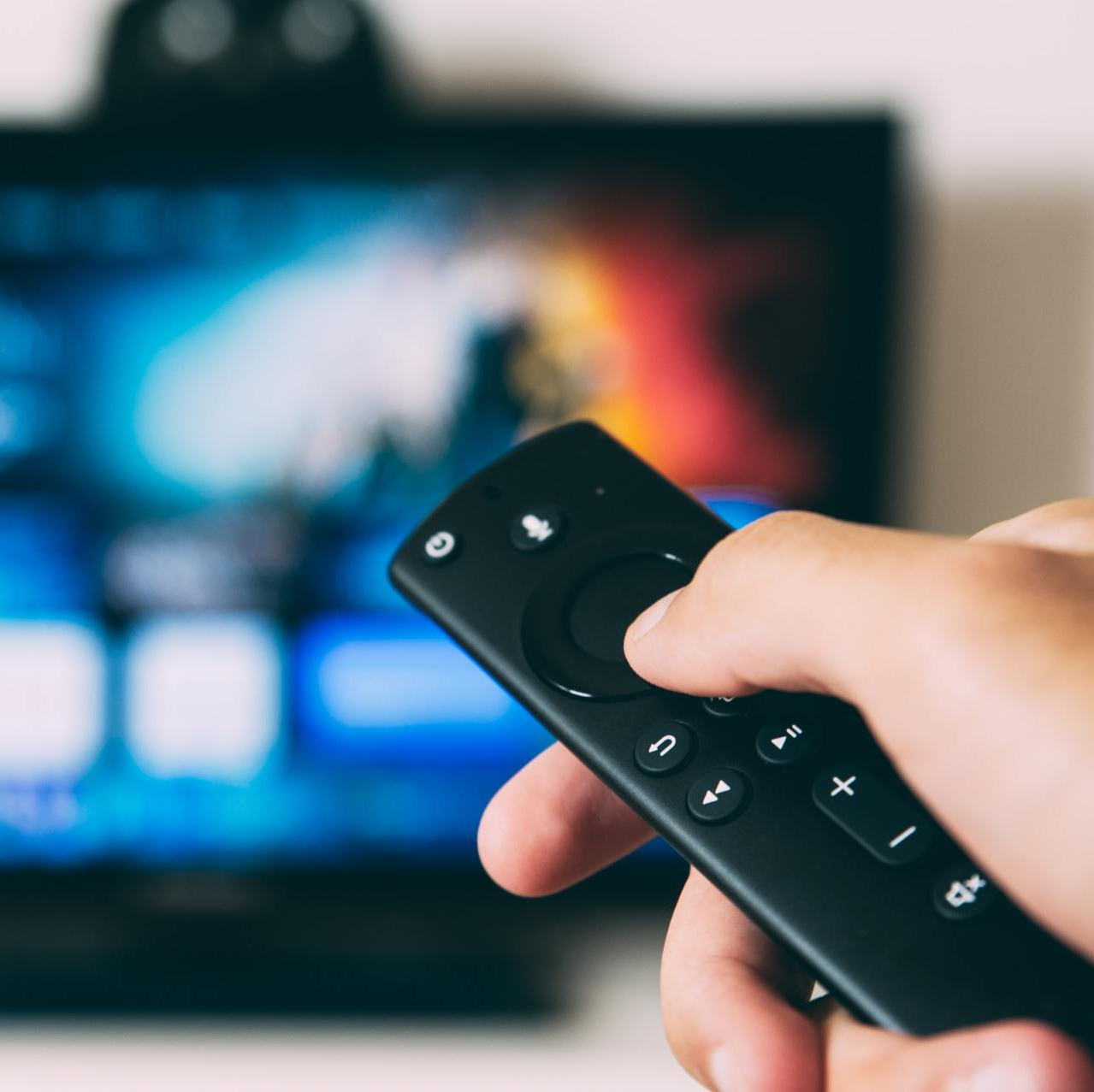 a person is holding a remote control in front of a tv
