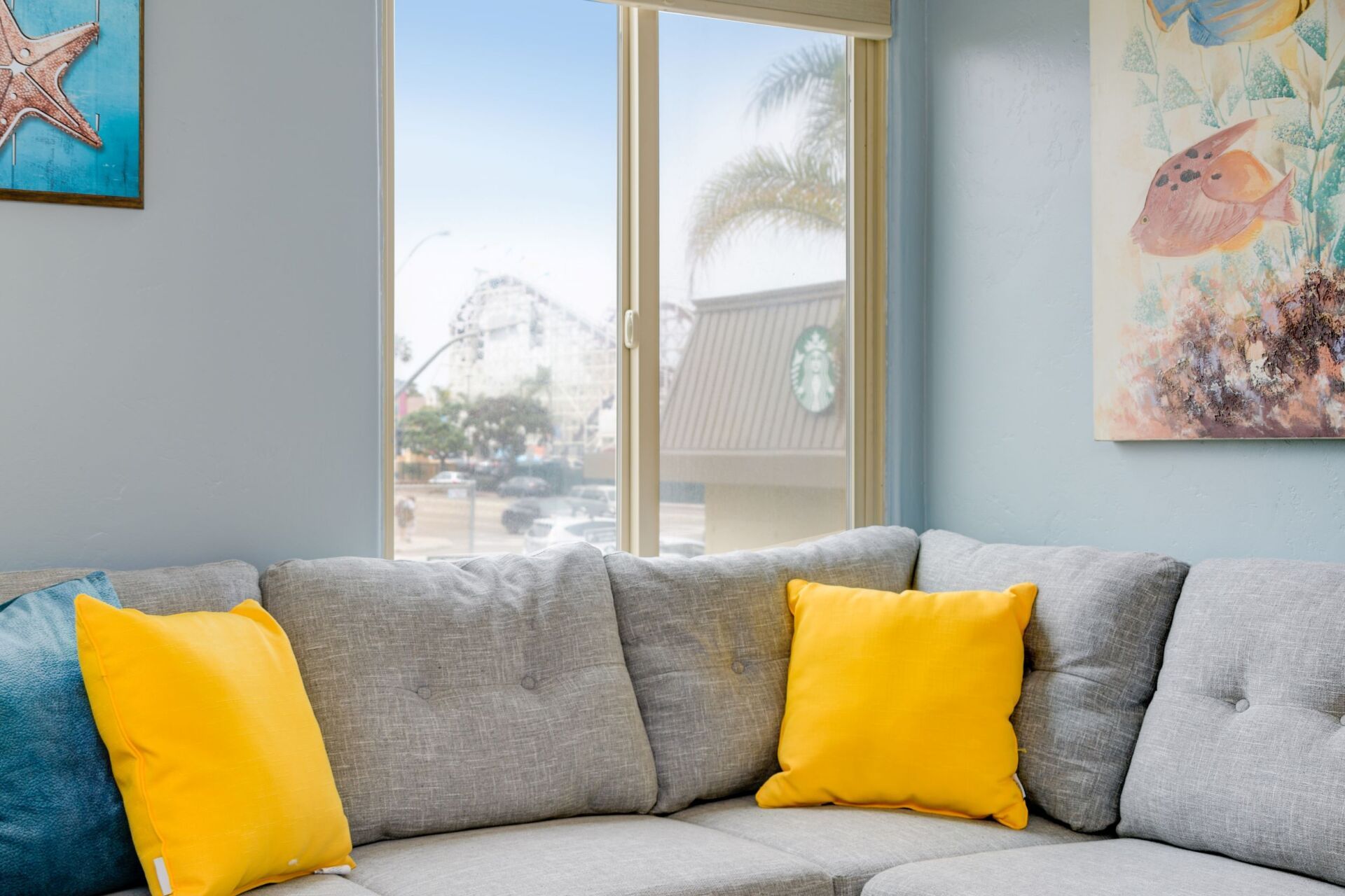 A living room with a couch , pillows and a painting on the wall.