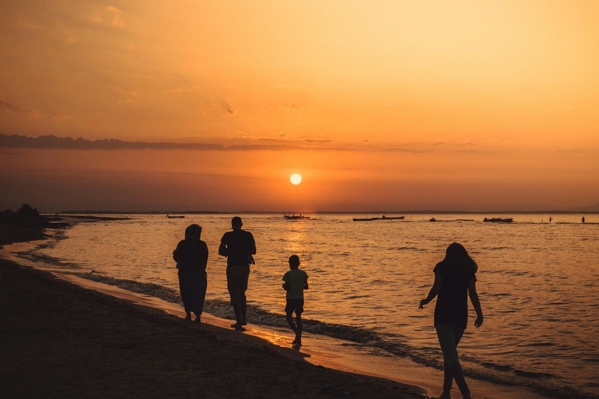 A family is walking on the beach at sunset.