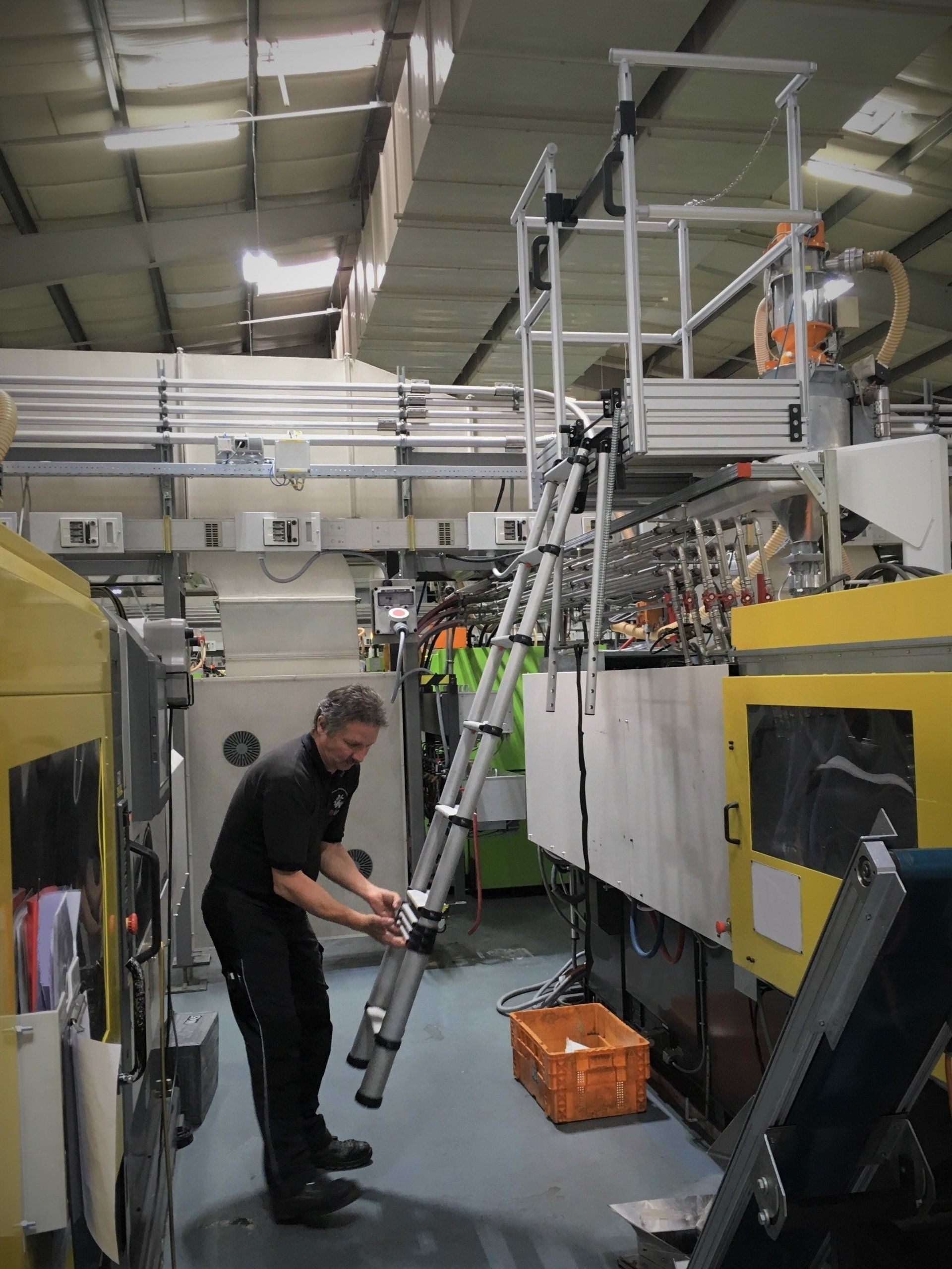 Ein Mann benutzt eine Leiter, um eine Maschine in einer Fabrik zu erreichen
