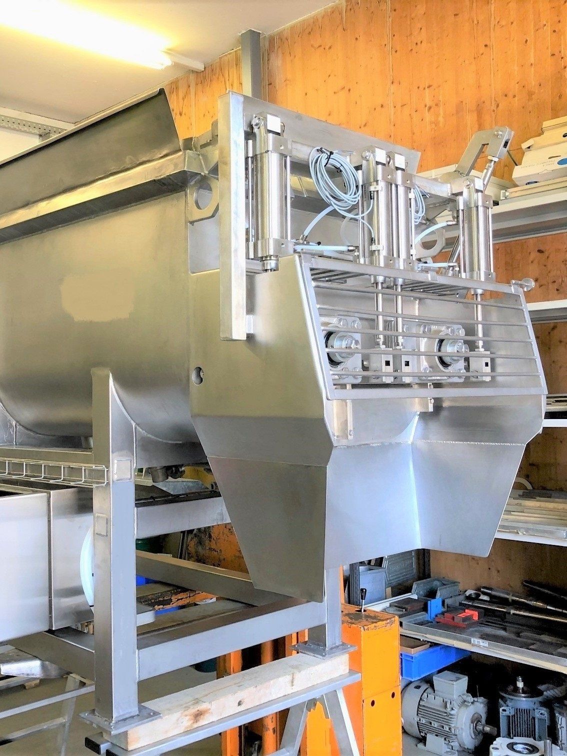 In einem Raum steht eine große Maschine aus Edelstahl auf einem Holztisch.