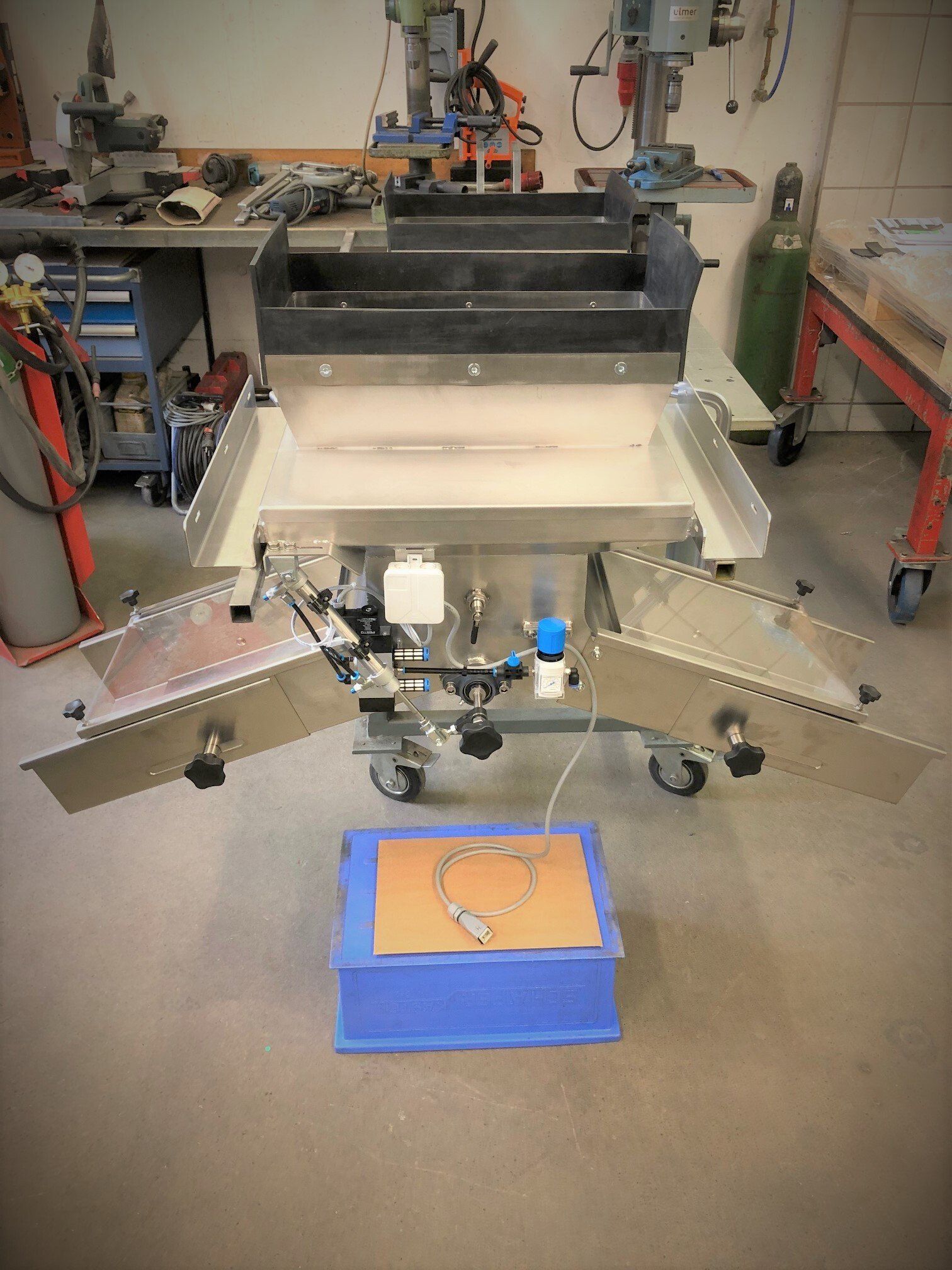 In einer Werkstatt steht eine Maschine auf einer blauen Kiste.