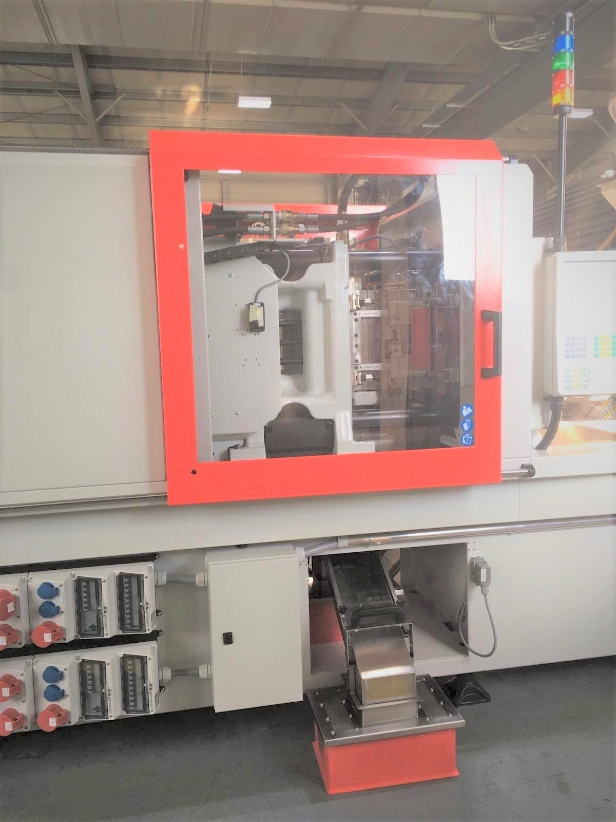 In einer Lagerhalle steht eine Maschine mit einer roten Tür.