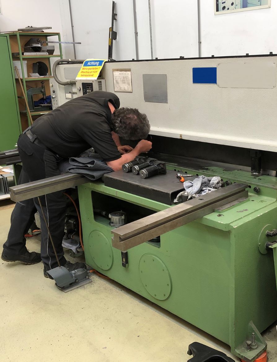 Zwei Männer arbeiten in einer Fabrik an einer Maschine.