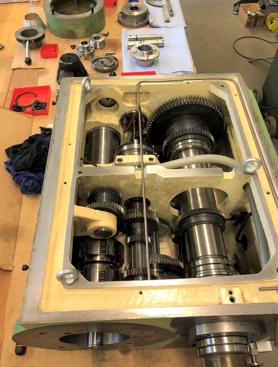 Auf einem Holztisch wird eine Maschine repariert.