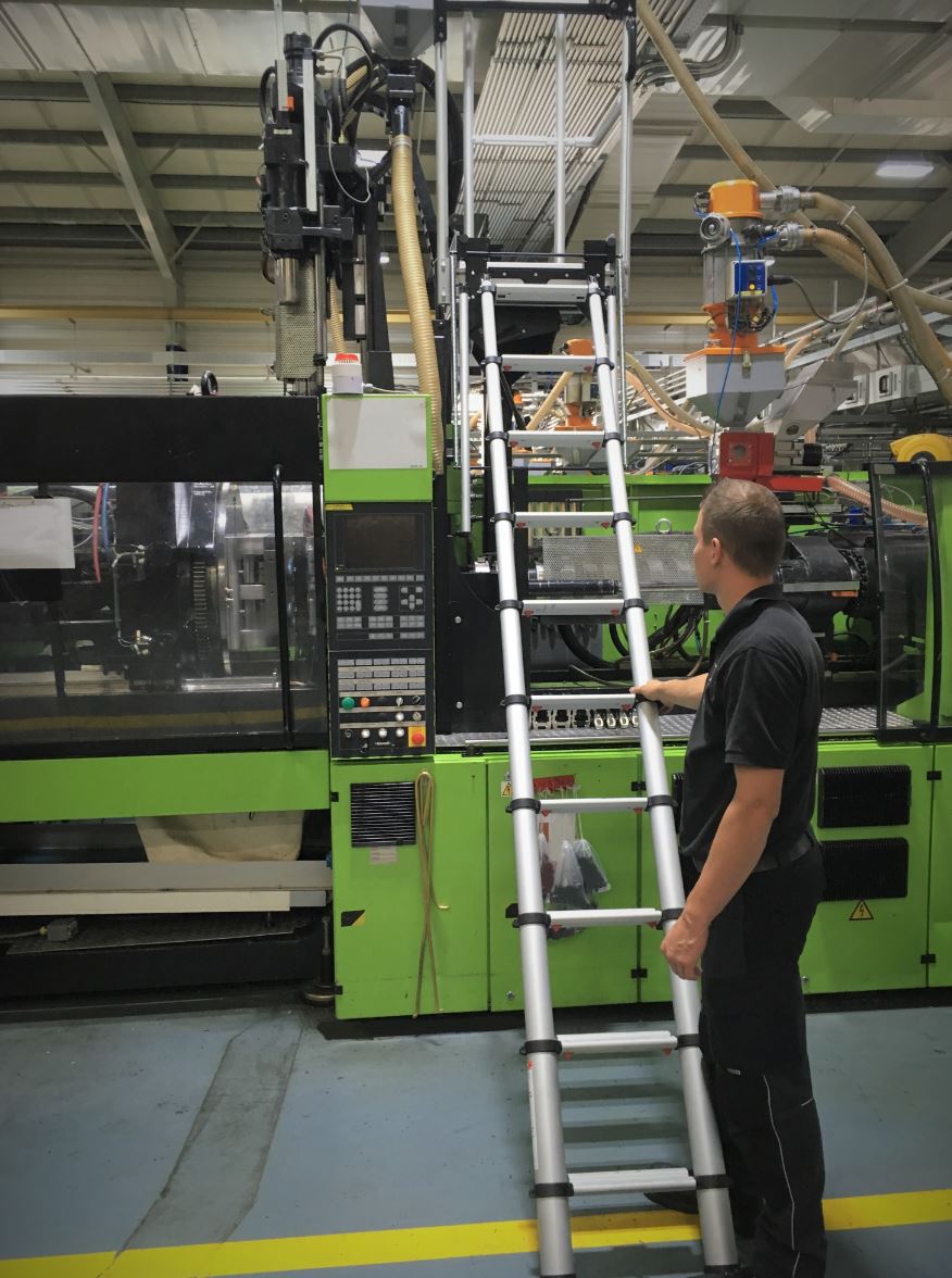 Ein Mann steht neben einer Leiter vor einer grünen Maschine