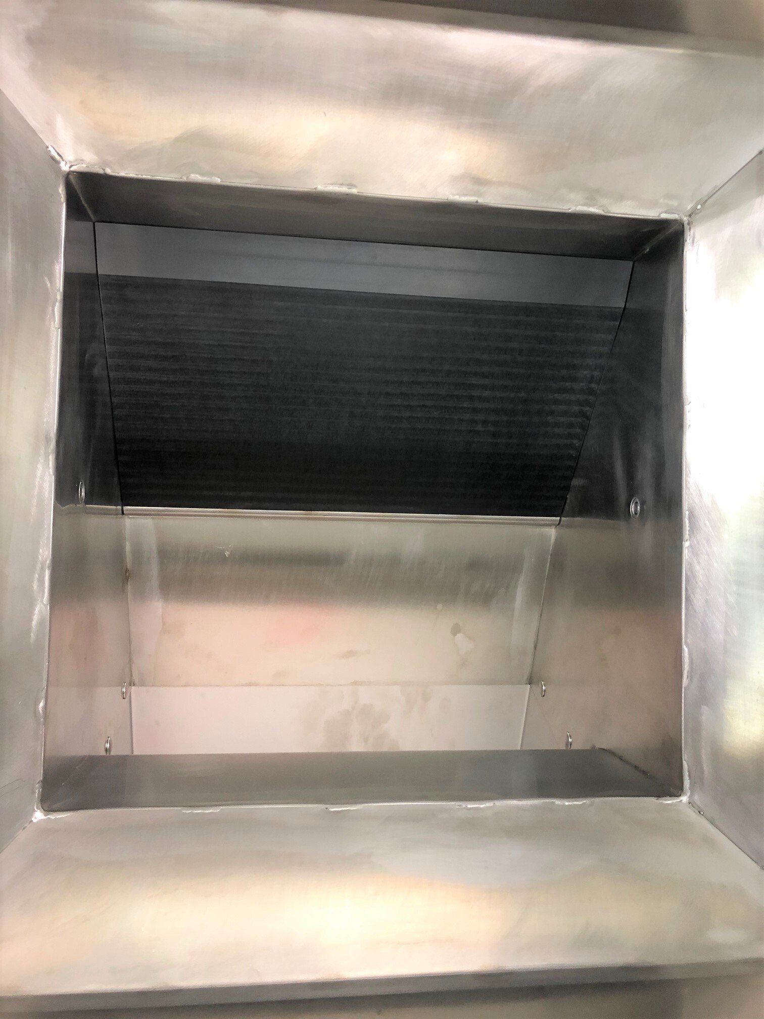 Das Innere eines Edelstahlkanals mit einem schwarzen Filter.