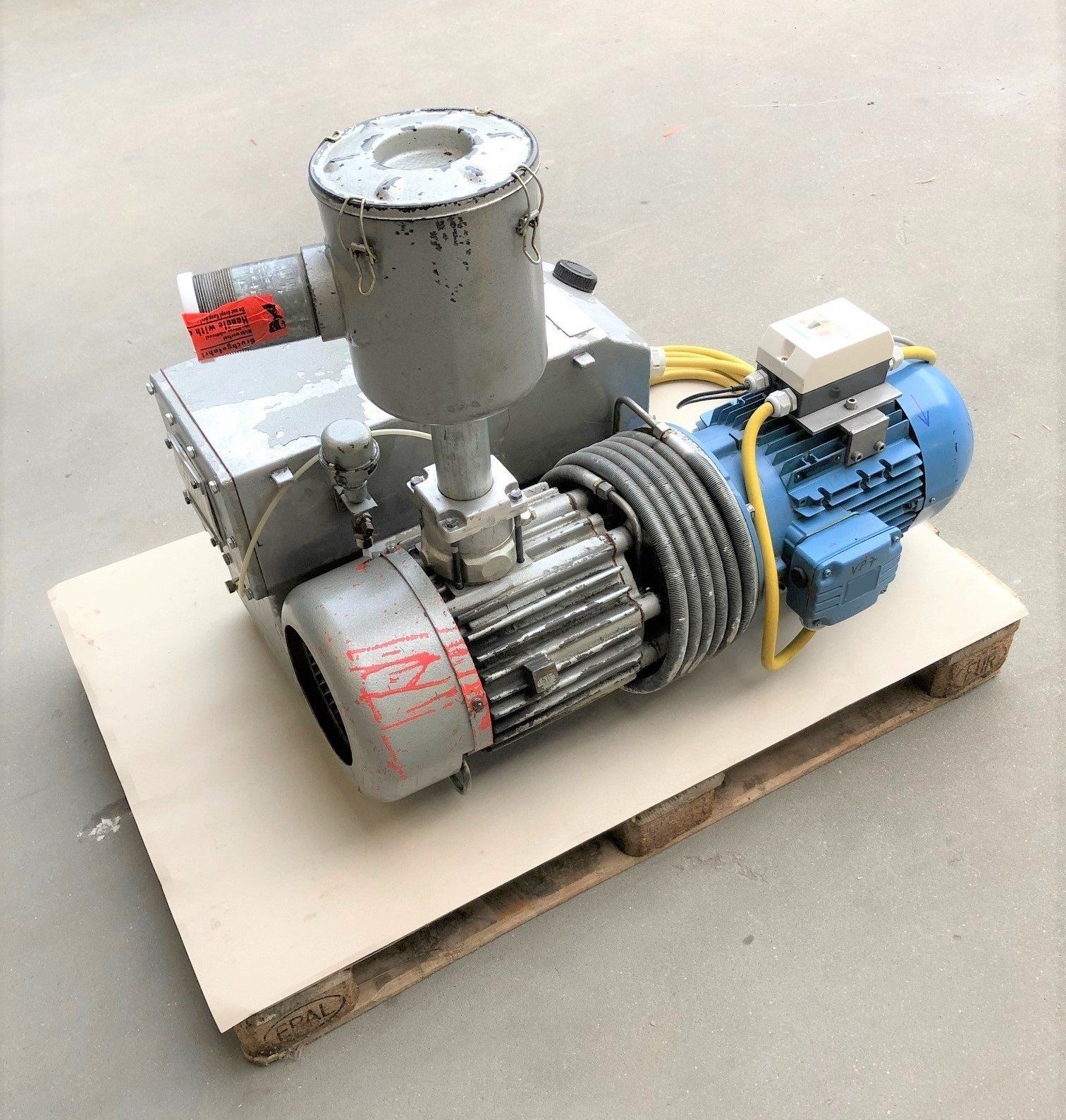 Auf einer Holzpalette steht eine Vakuumpumpe.