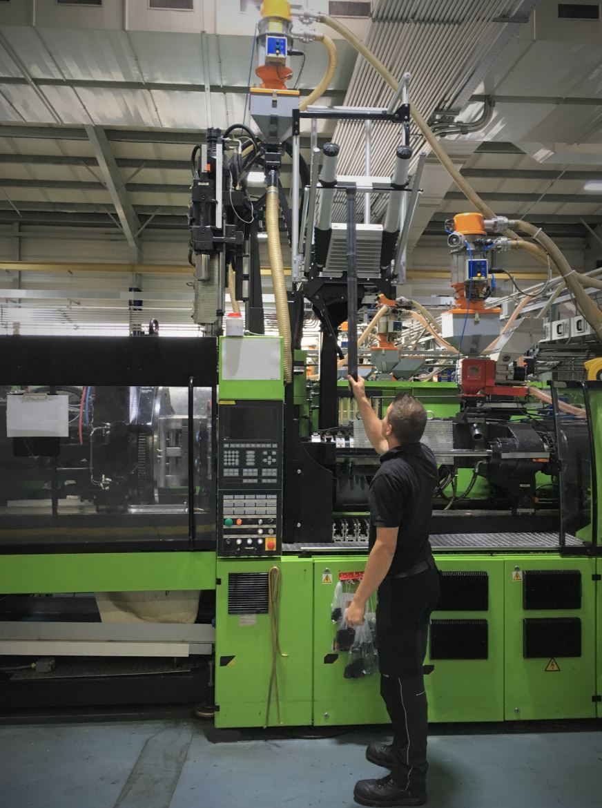 Ein Mann arbeitet in einer Fabrik an einer grünen Maschine