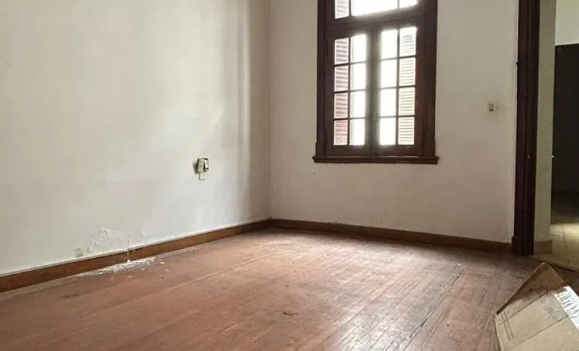 Pequeña cocina con estufa de gas, fregadero, piso de baldosas y una puerta que da a una luminosa zona exterior.