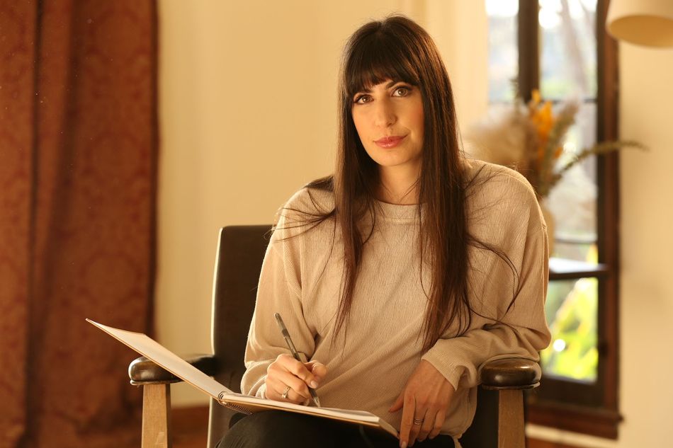 A woman is sitting in a chair writing on a piece of paper.