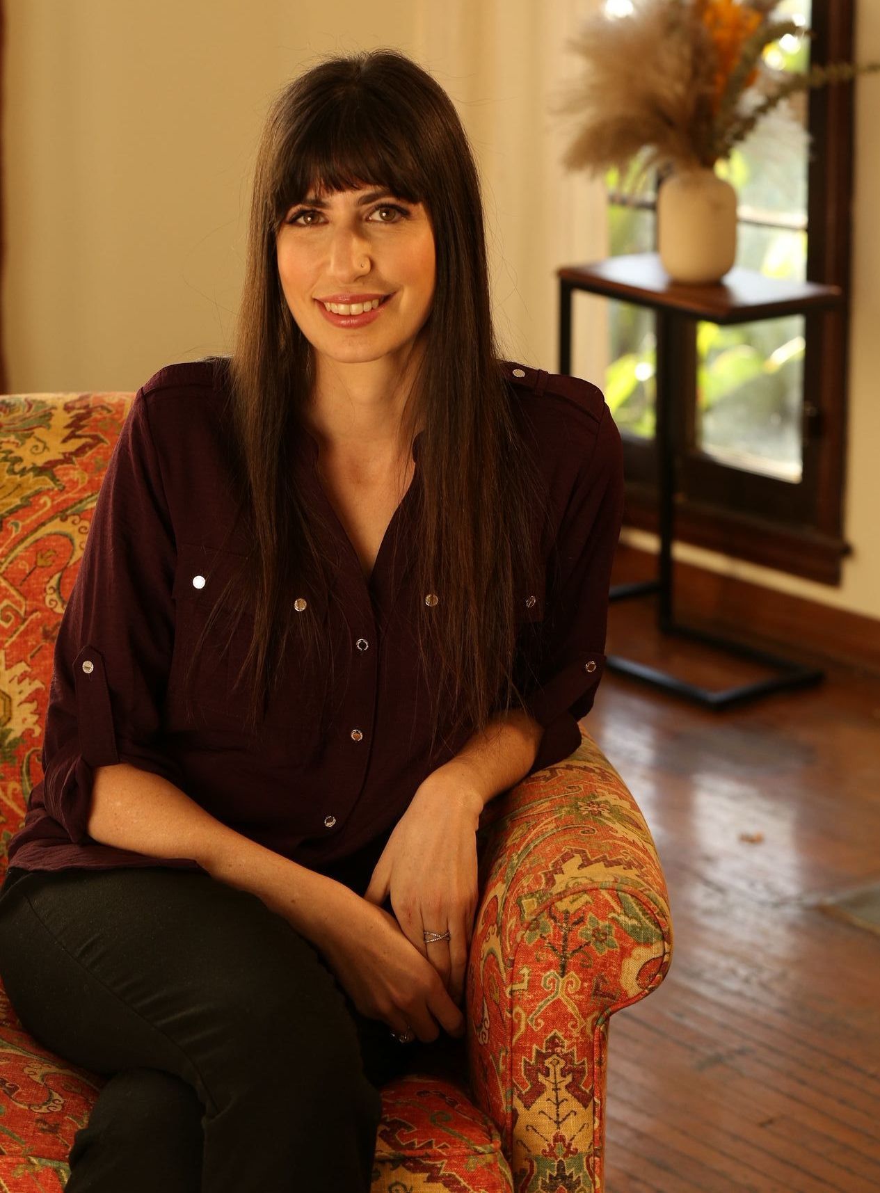 A woman is sitting in a chair in front of a window.