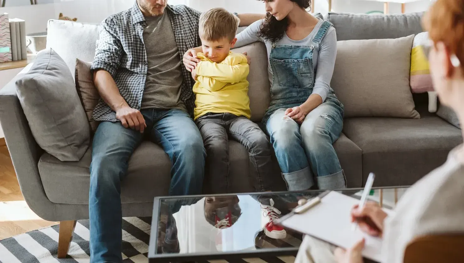A family is sitting on a couch talking to a counselor.