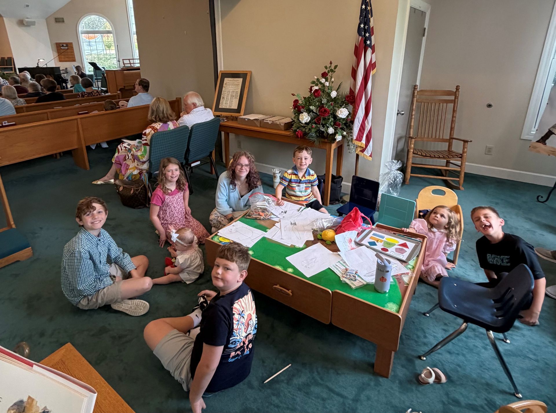 People playing cornhole and socializing on an outdoor patio with artificial grass and exposed brick.