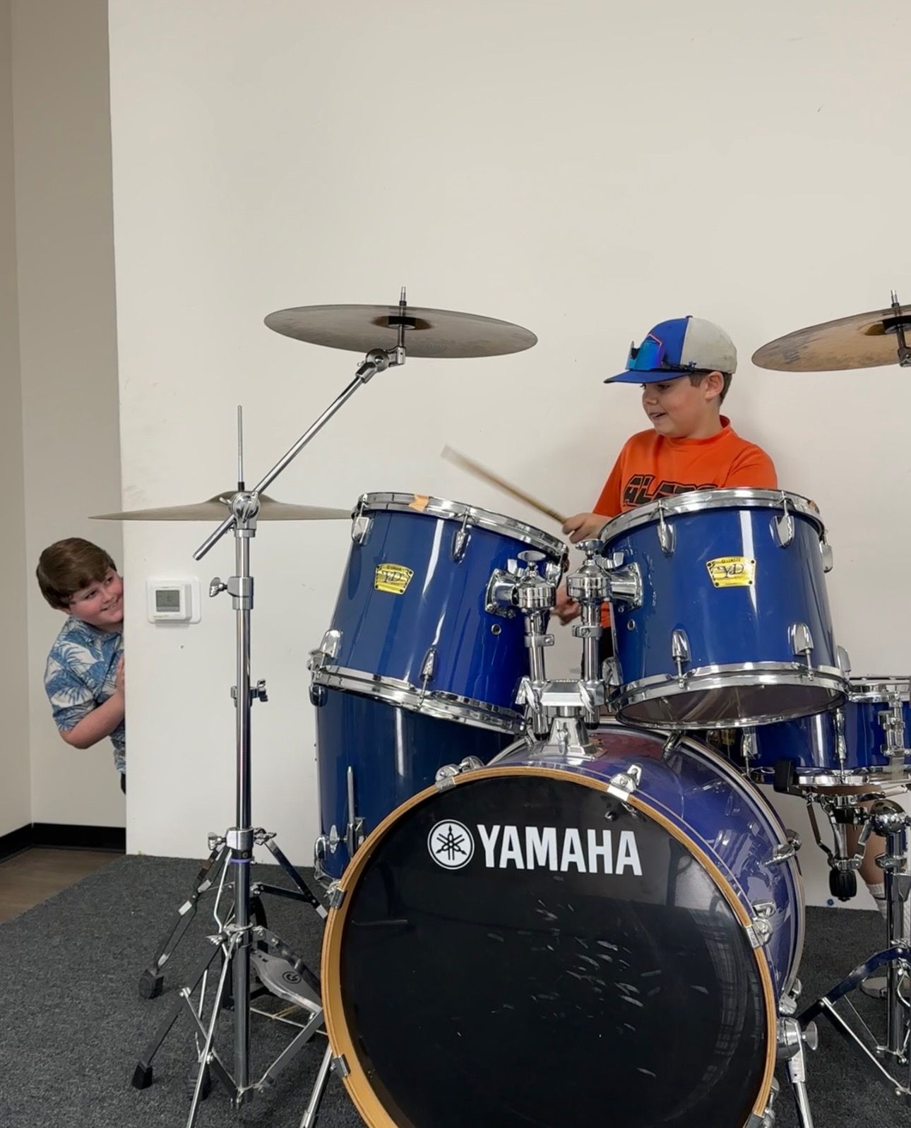 A girl wearing a purple sweatshirt and a white beanie is holding a donut.