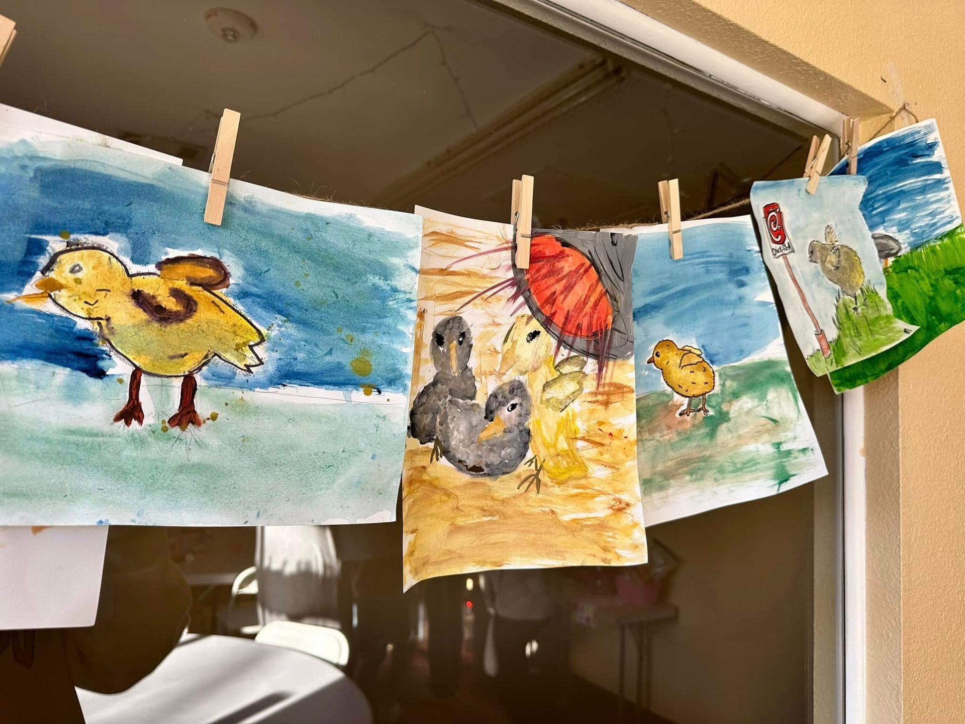 Children 's drawings of chickens are hanging on a clothes line