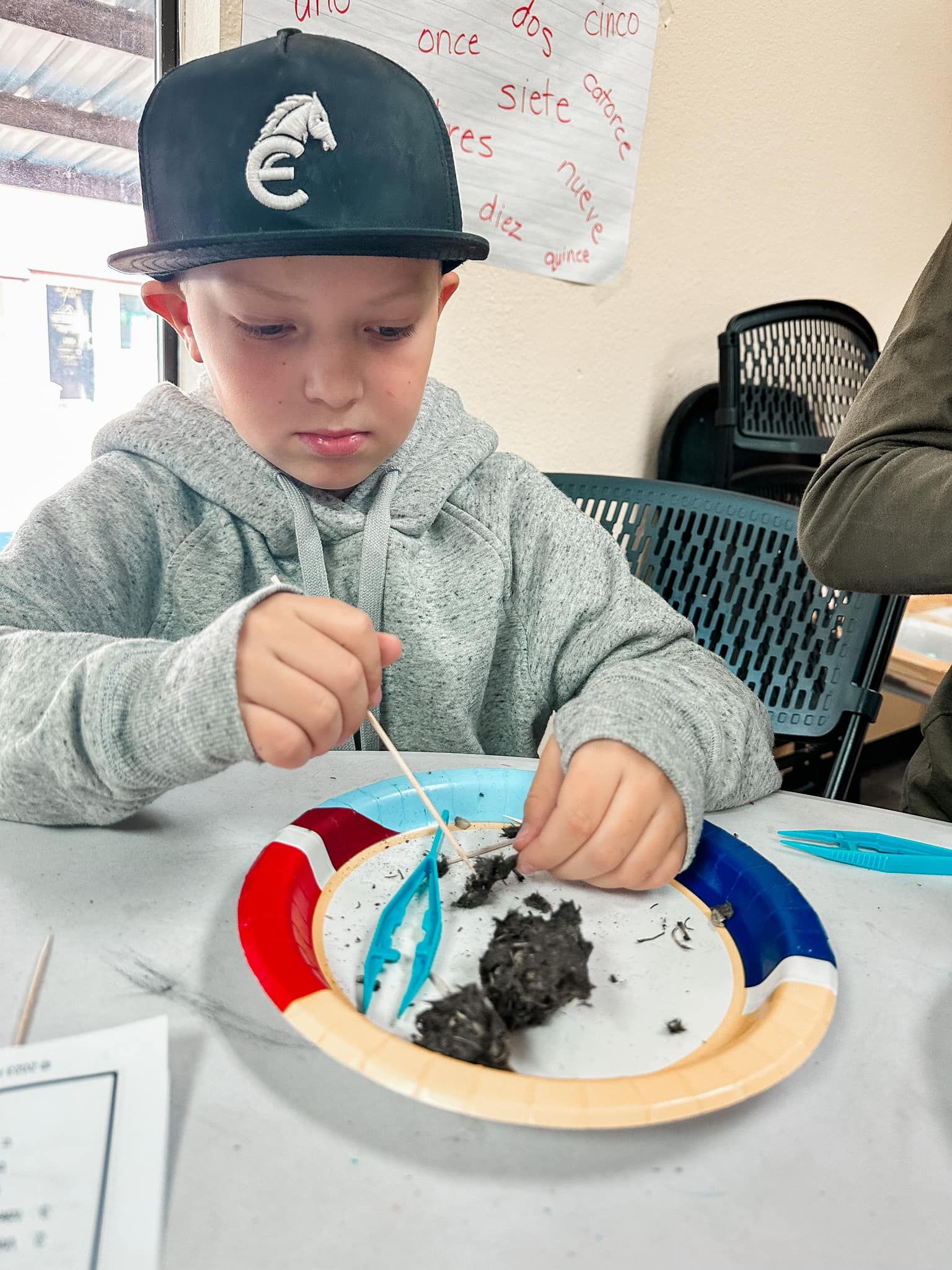 A young boy wearing a hat with the letter c on it