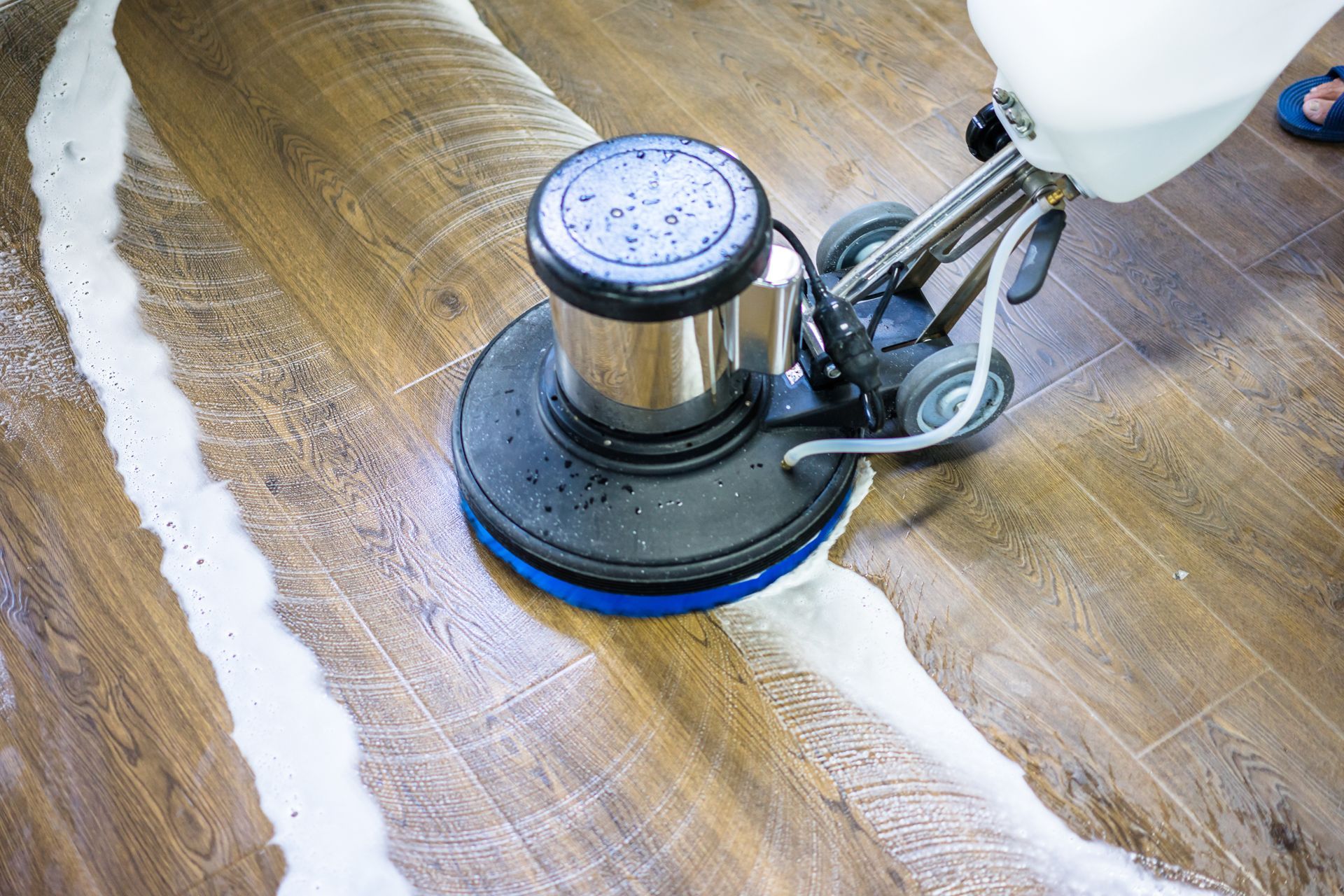 A person is using a machine to clean a wooden floor.
