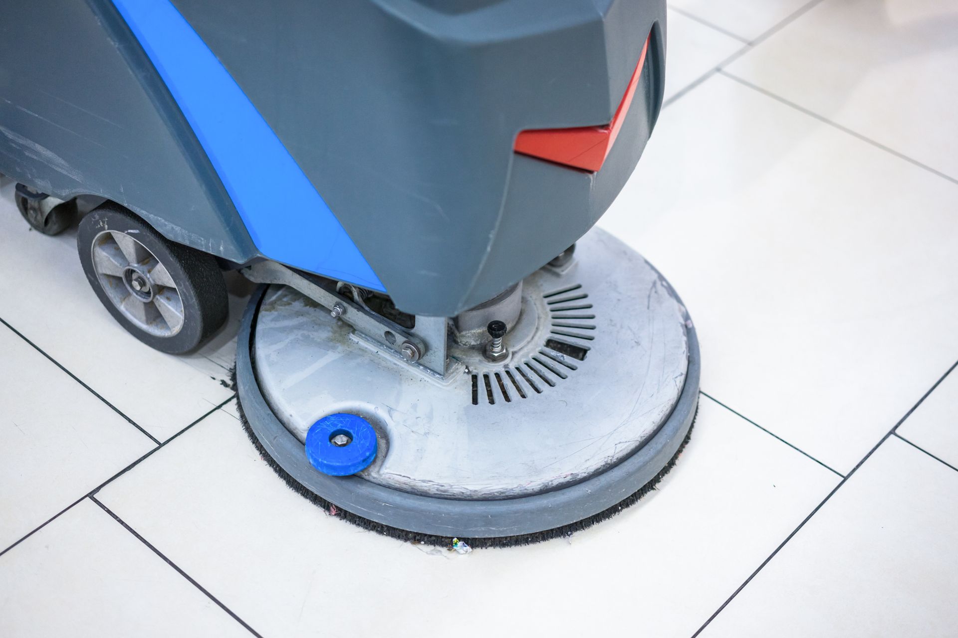 A machine is cleaning a tiled floor in a building.