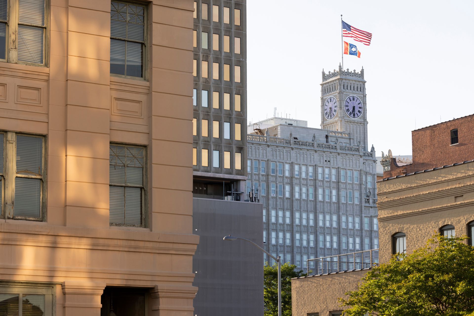 Buildings in an urban setting, including a clock tower with American flag.