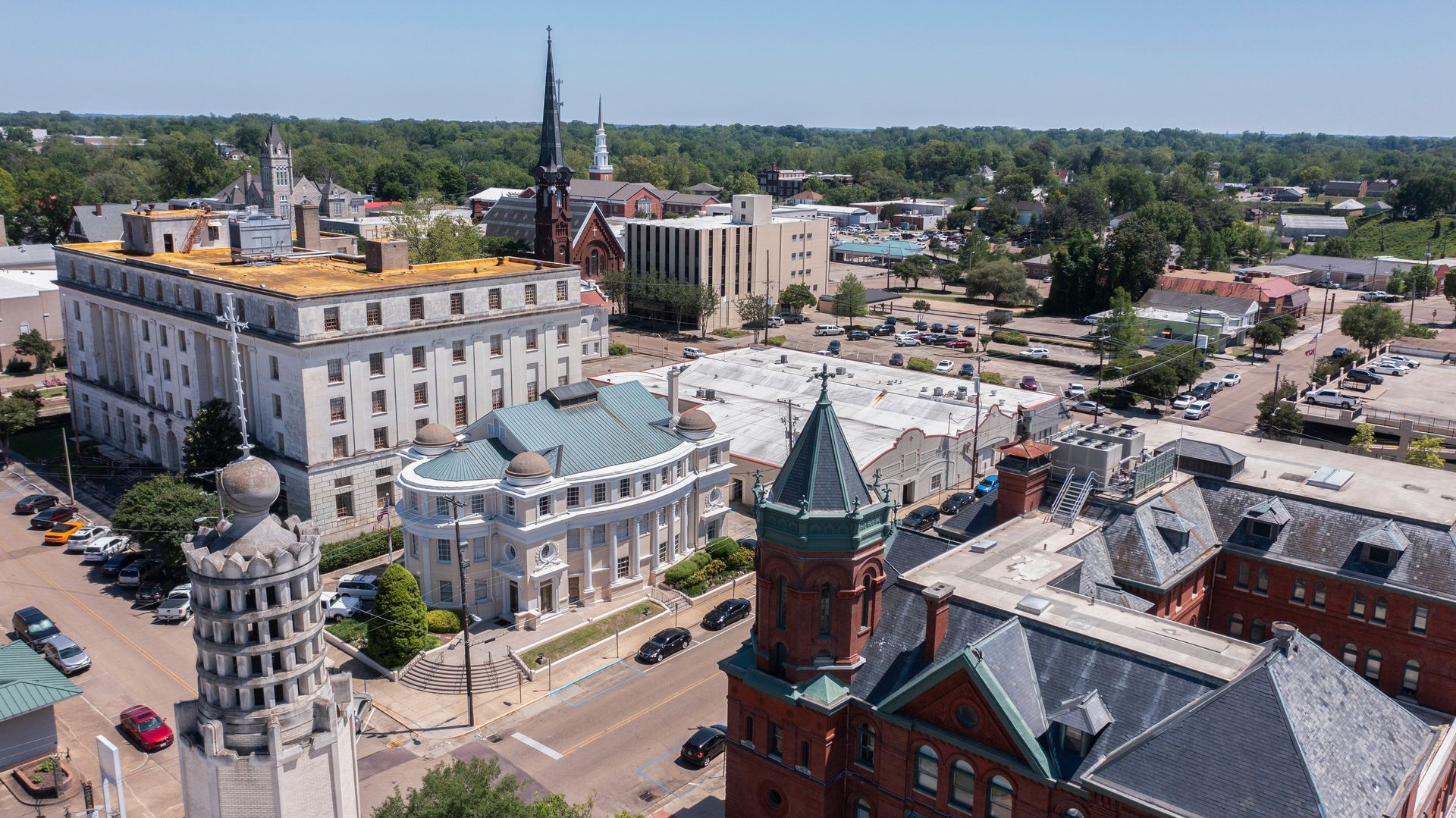 Aerial view of a city with several large buildings, including a white, ornate building with a copper roof.