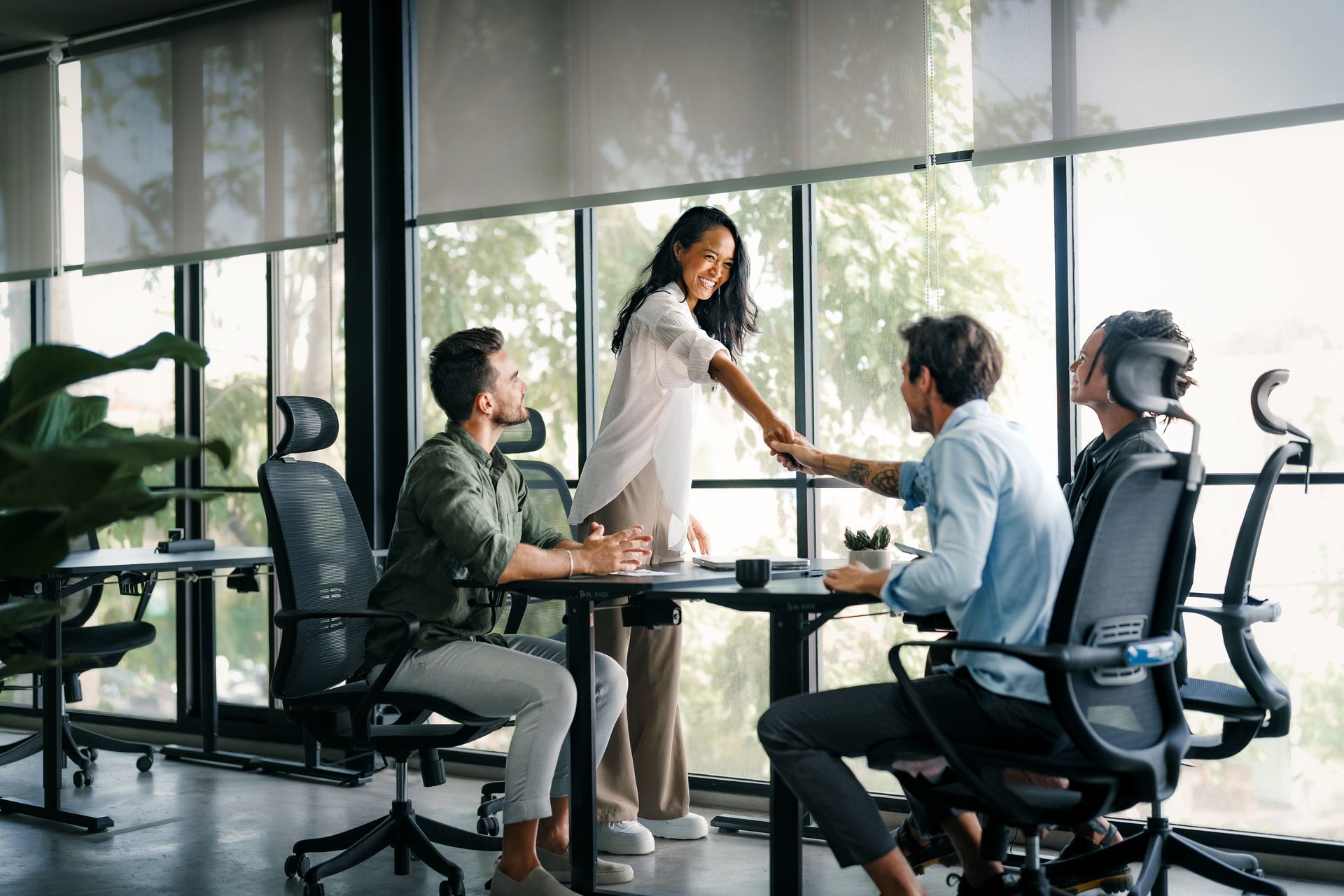 Four people at a table, one shaking hands. 