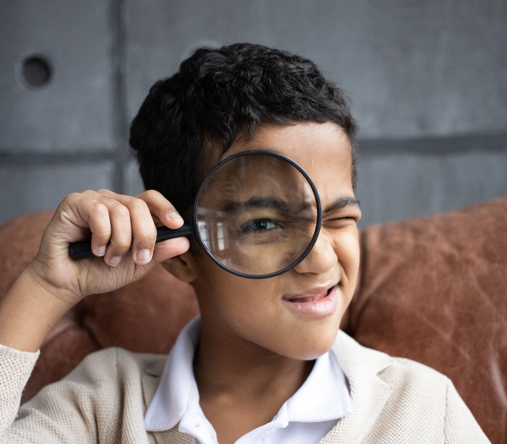 A young boy is looking through a magnifying glass at something