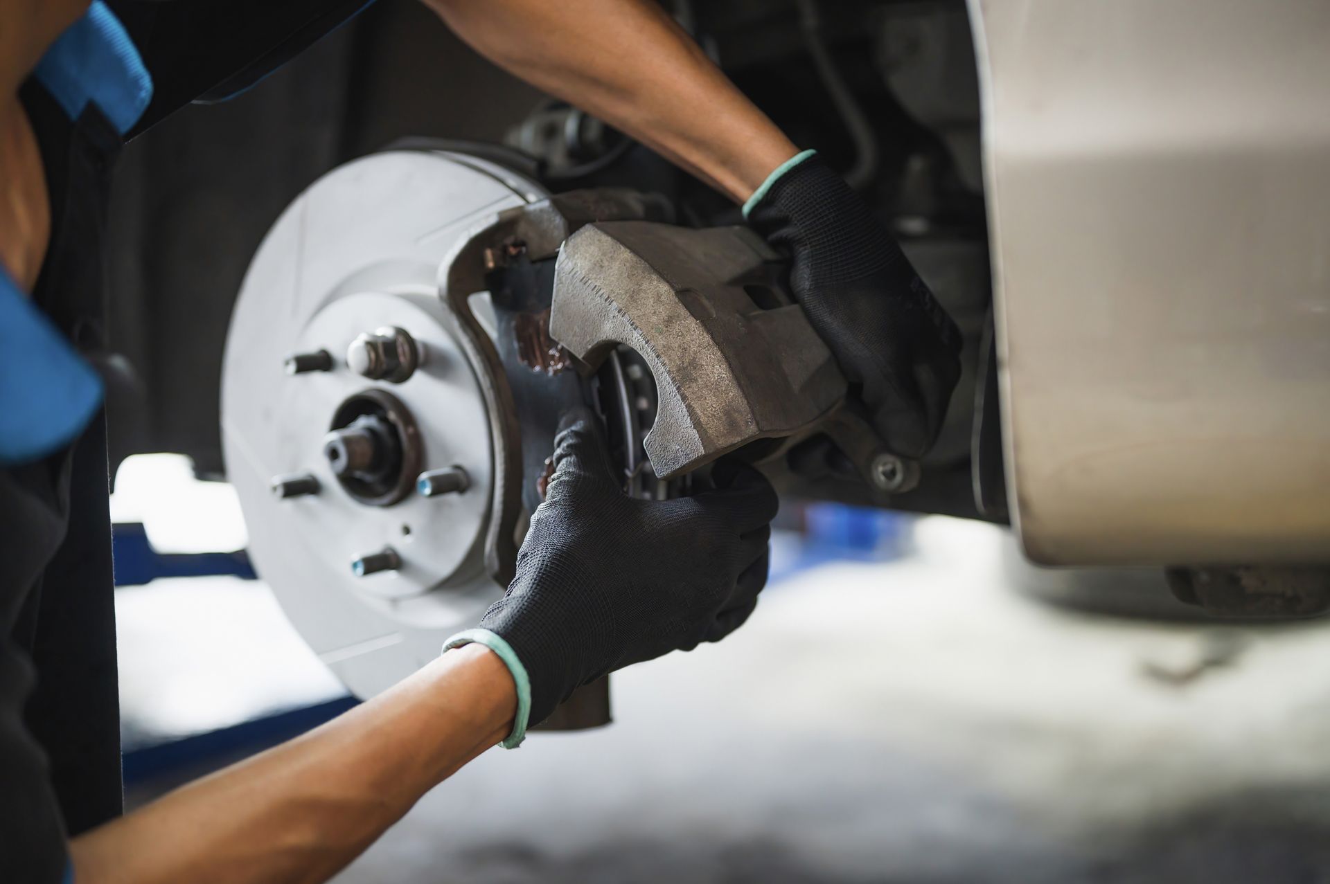 A man is fixing the brake pads on a car | National Automotive Repair