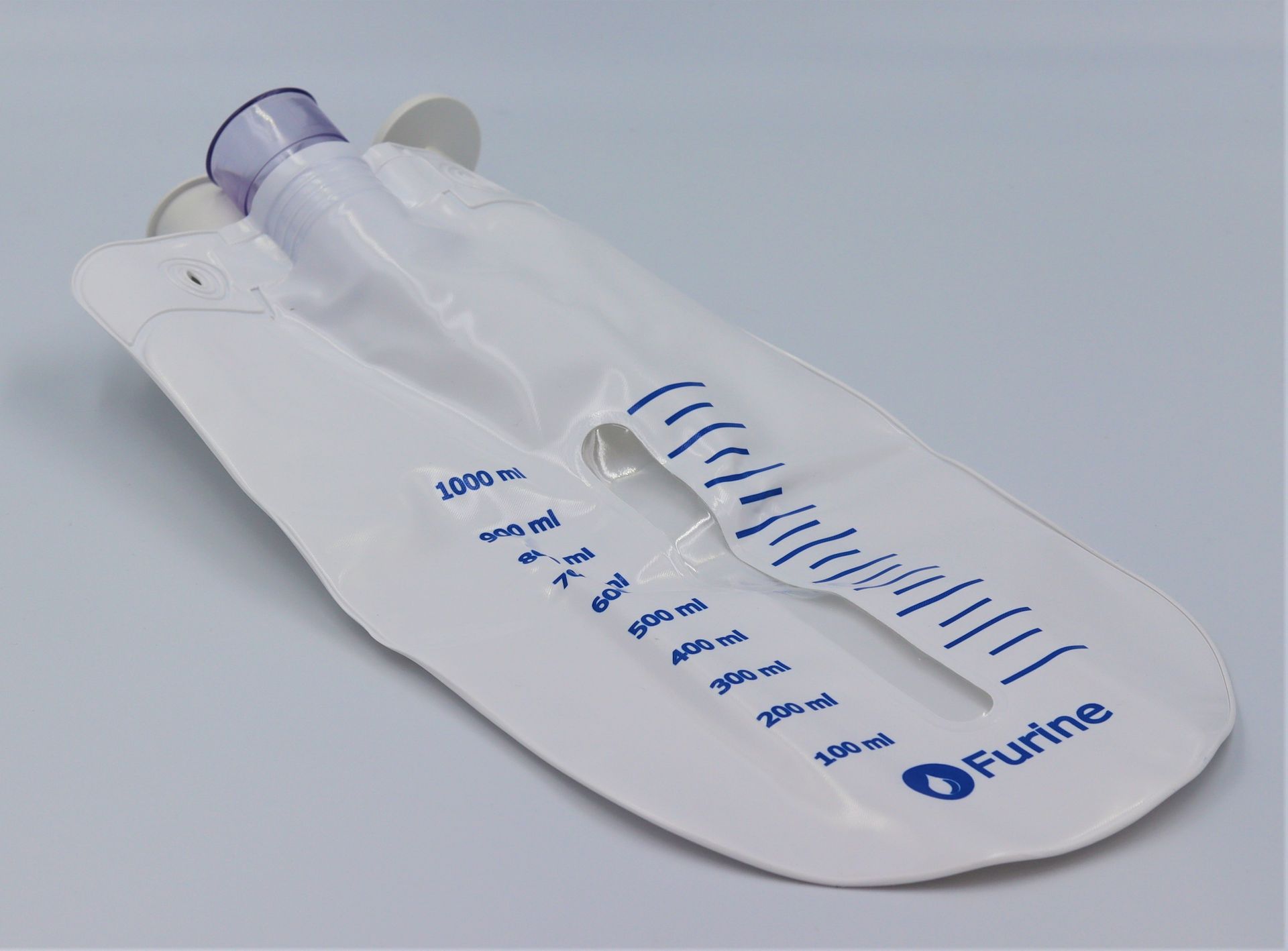 Clear plastic urine collection bag on a white absorbent pad with blue measurement markings