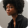 A woman with afro hair is wearing a black jacket.