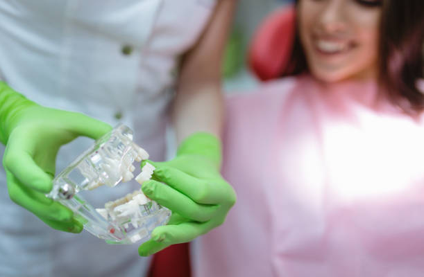 Person in green gloves holding clear dental aligners.