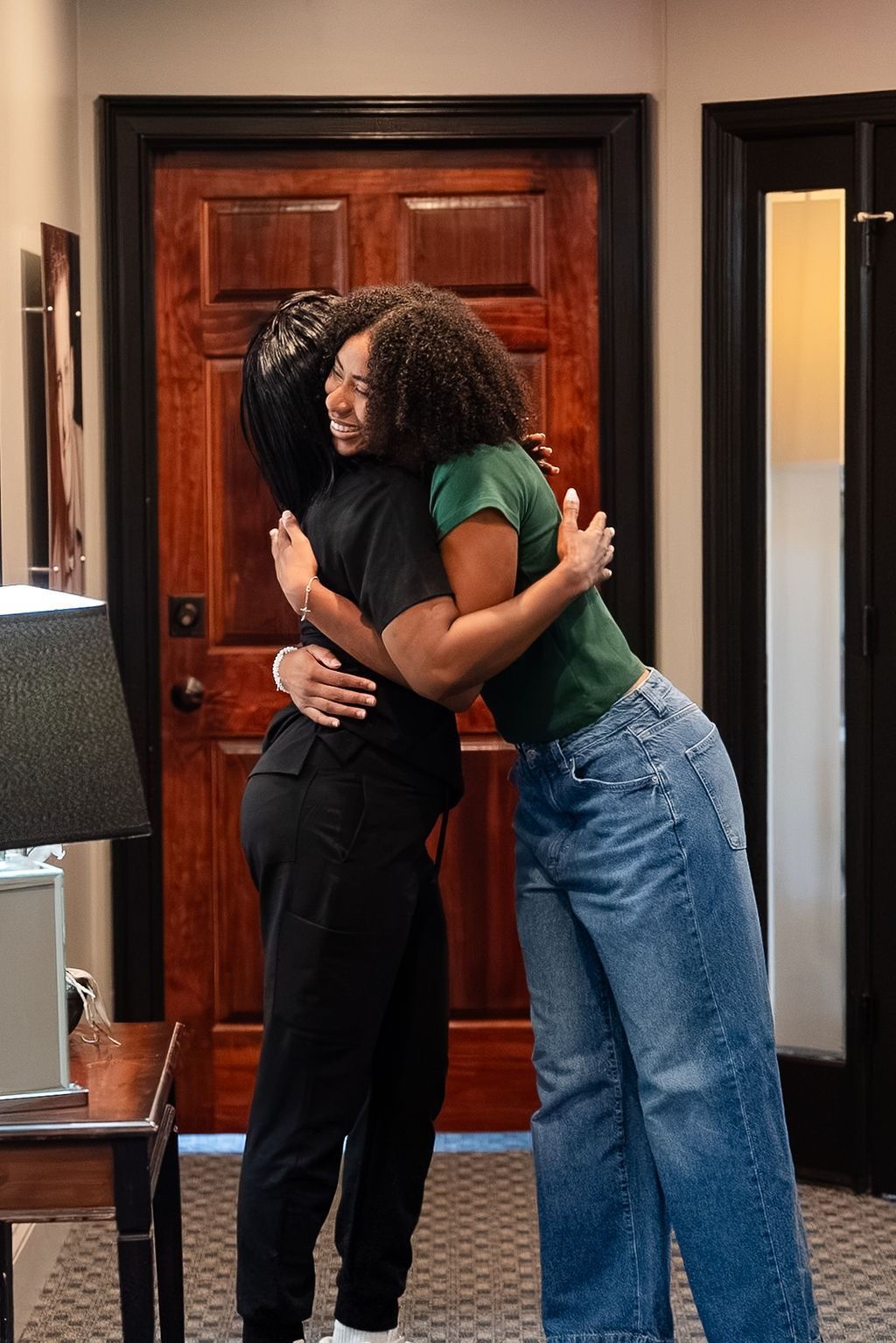 Two people hugging indoors in front of a wooden door