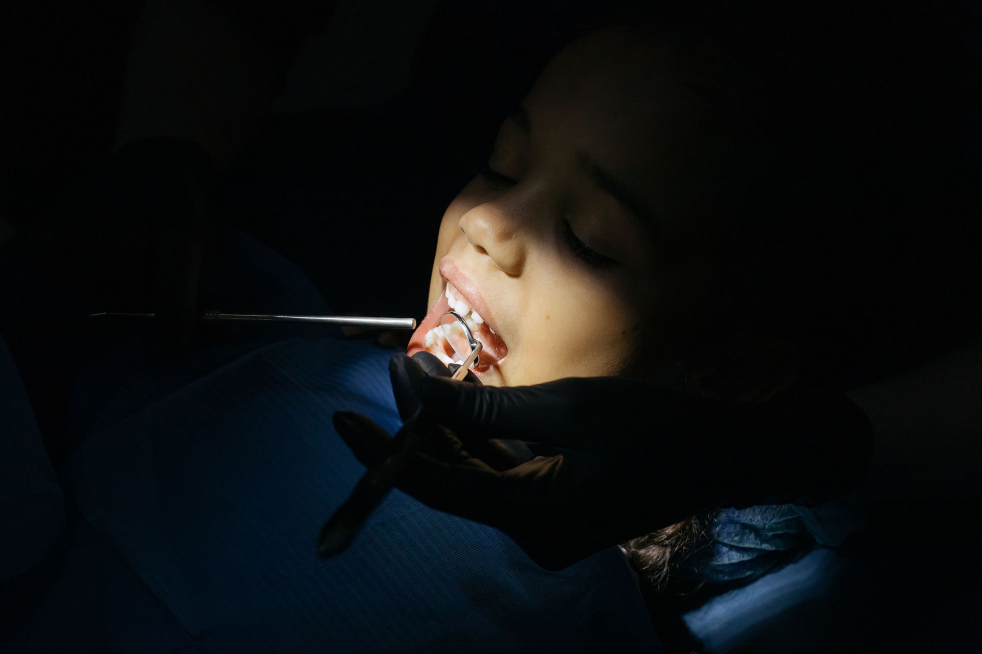Person lying in a dark setting with a face mask and a bright light on their face.