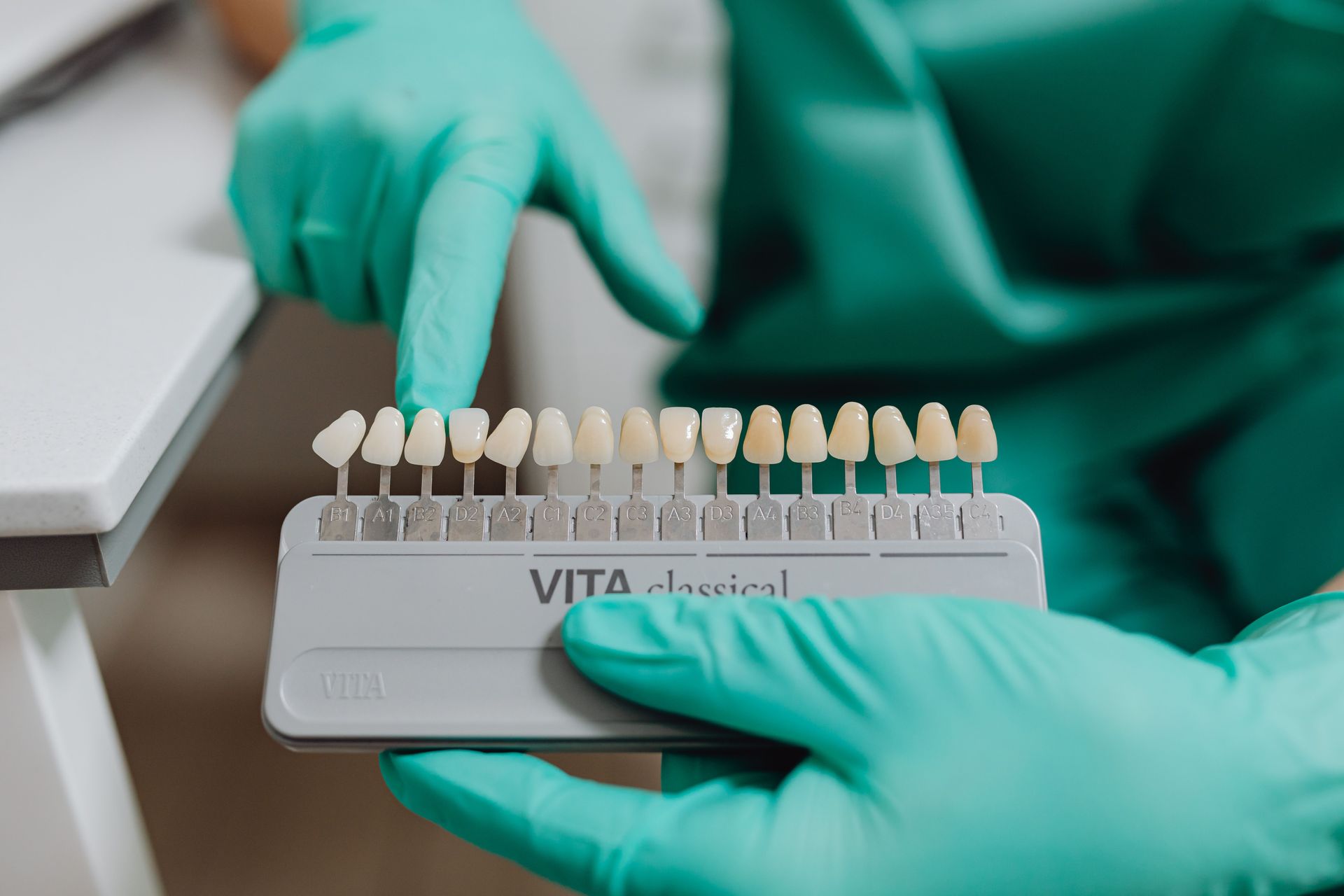 Gloved hands holding a shade guide of teeth samples in a dental lab.