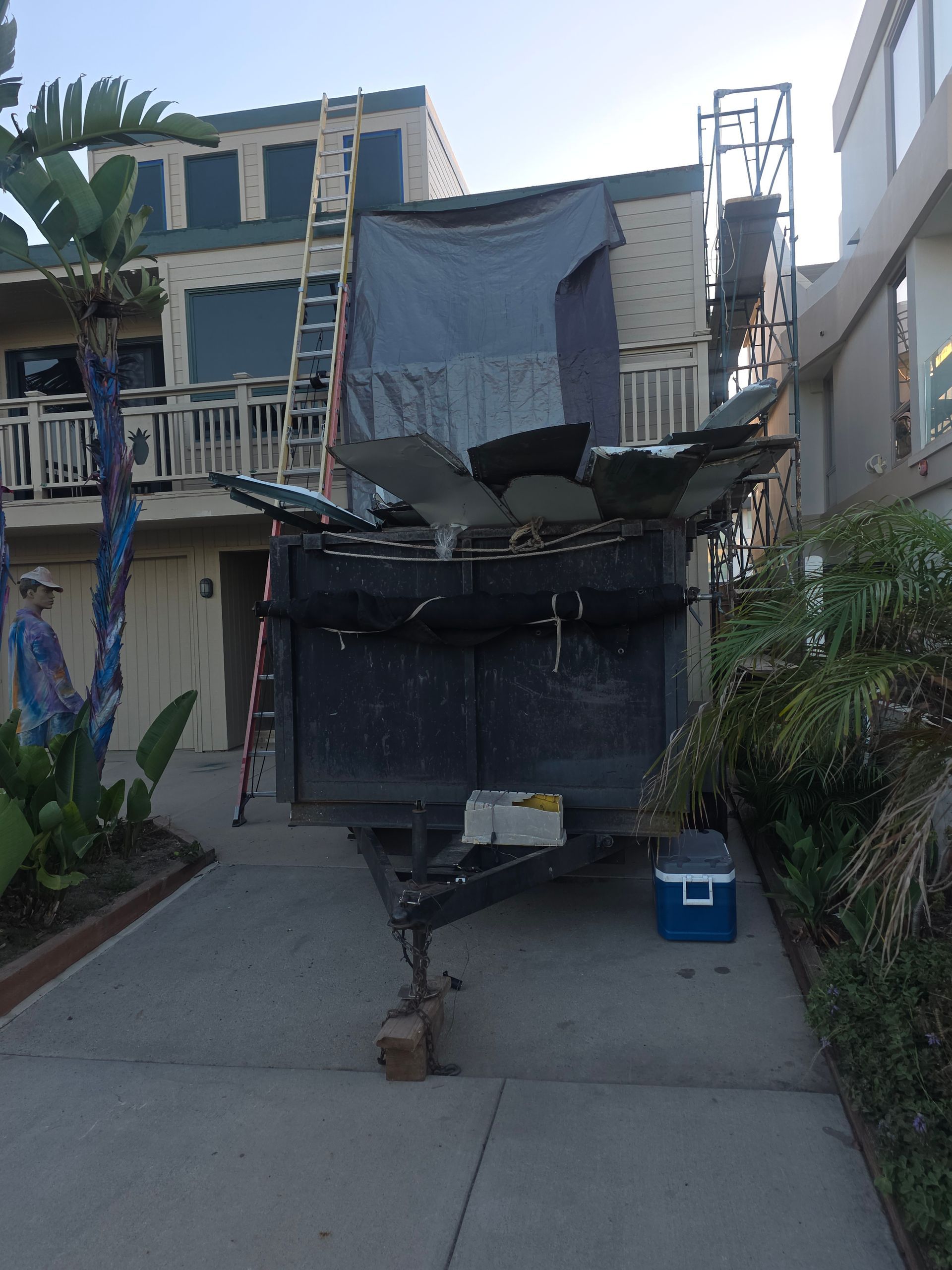 Roof replacement in process with dumpster and ladders