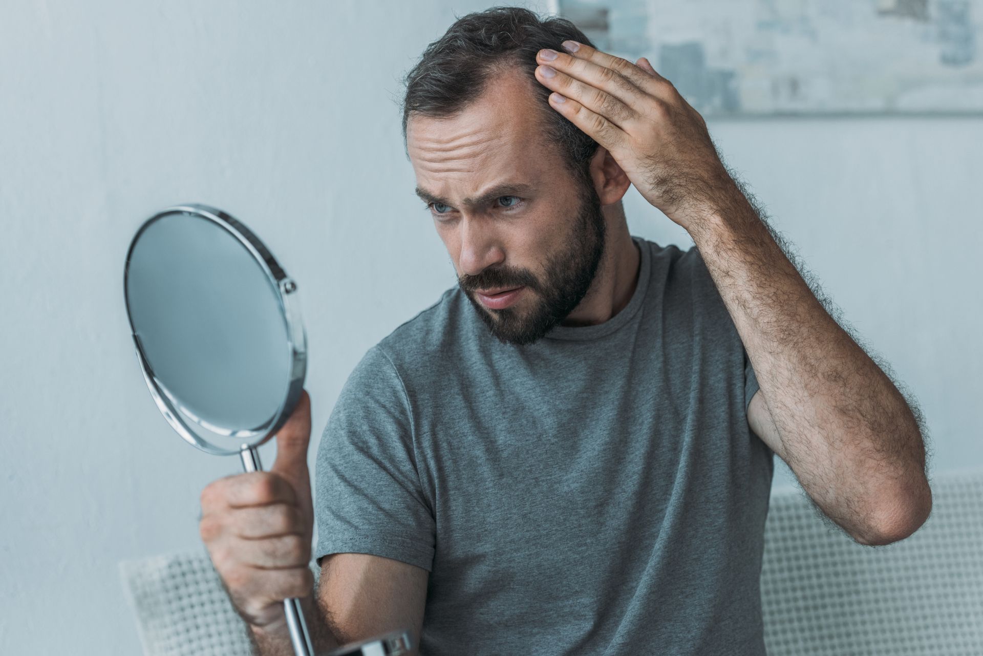 A man is looking at his hair in a mirror after a hair loss treatment