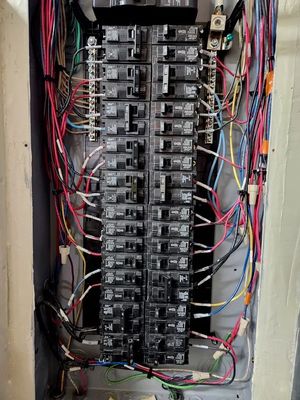 A close up of a electrical panel with a lot of wires coming out of it.