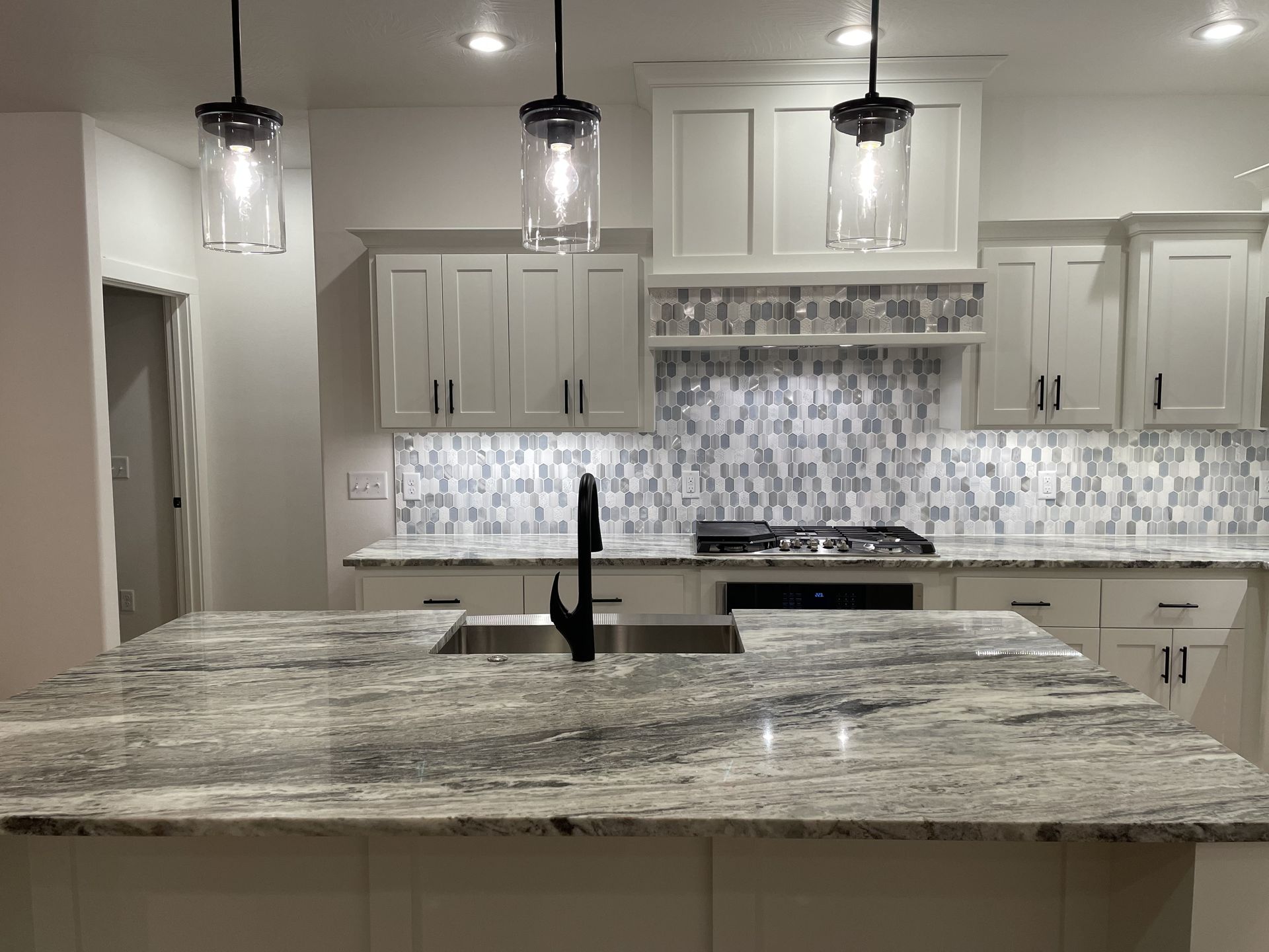A kitchen with white cabinets , granite counter tops , a sink and a stove.