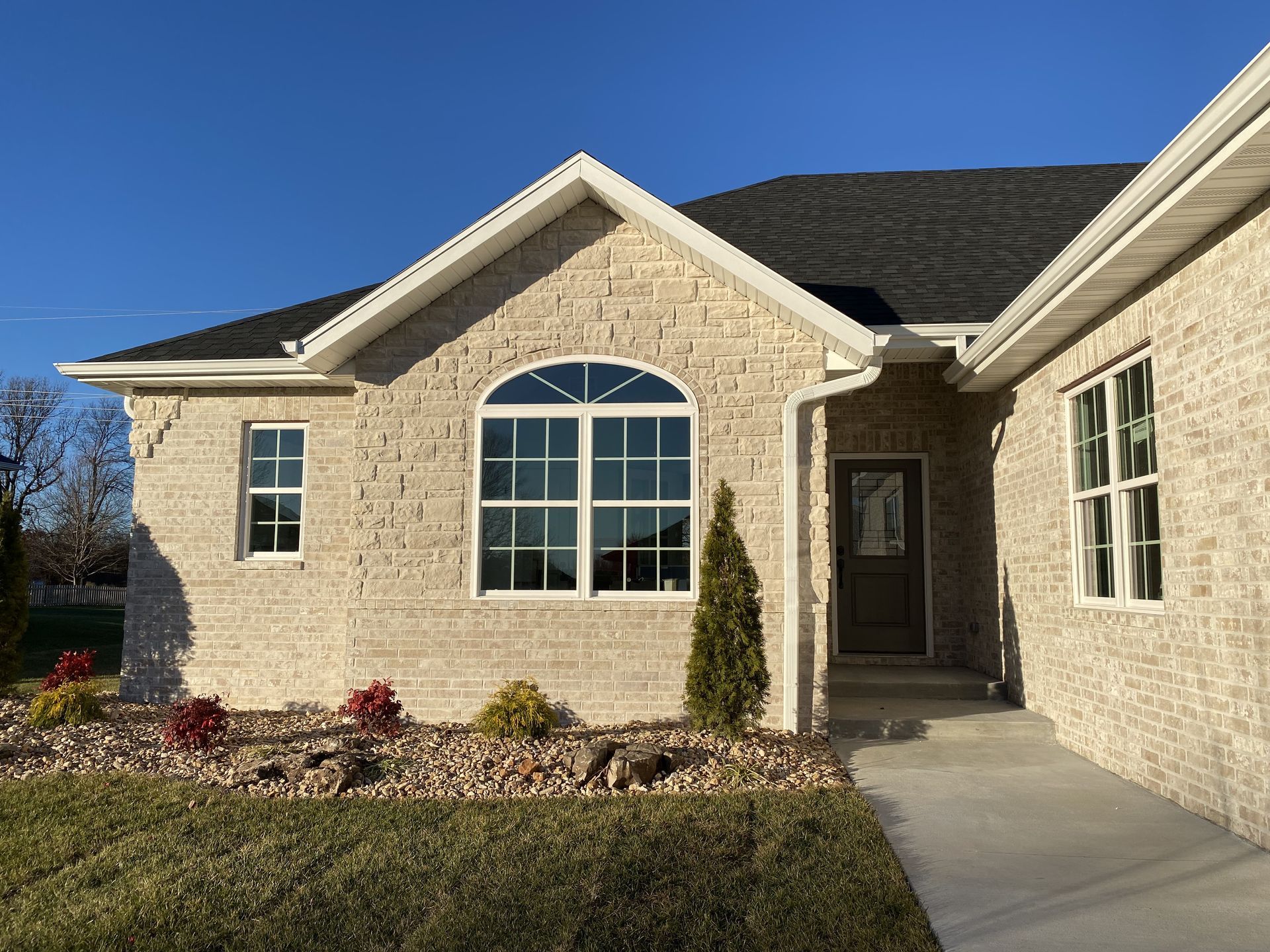A brick house with a black roof and white trim