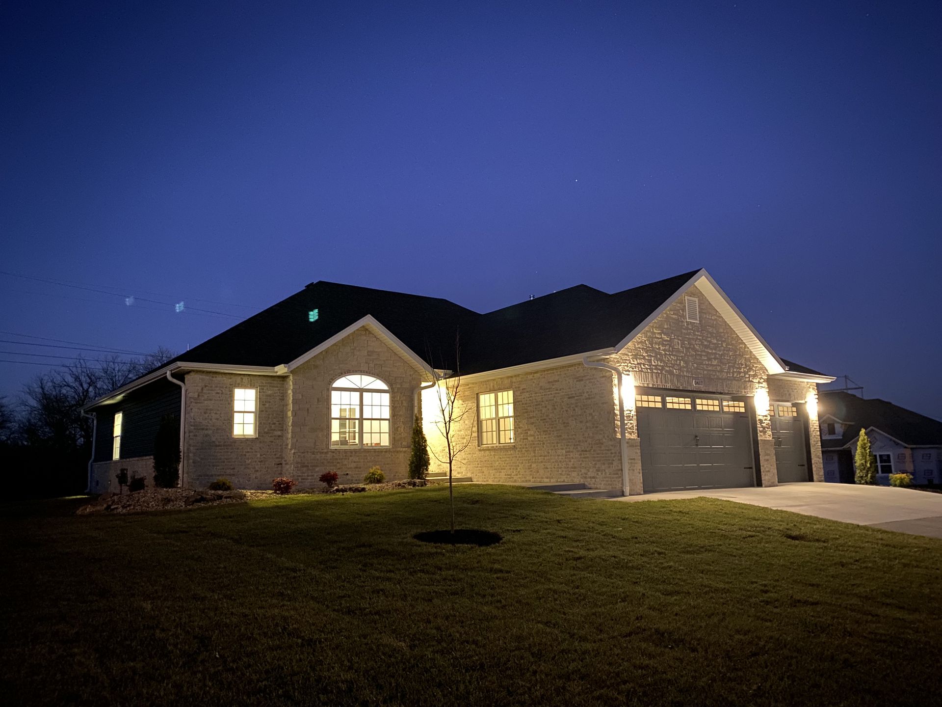 A house is lit up at night with a blue sky in the background