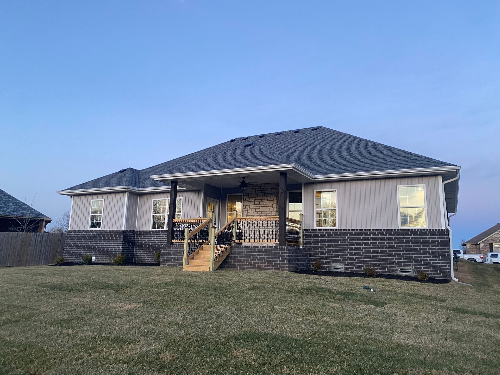A house with a gray roof is sitting on top of a lush green field.
