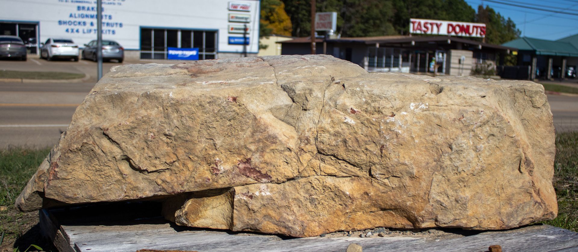 A large rock is sitting in front of a rusty powder store.