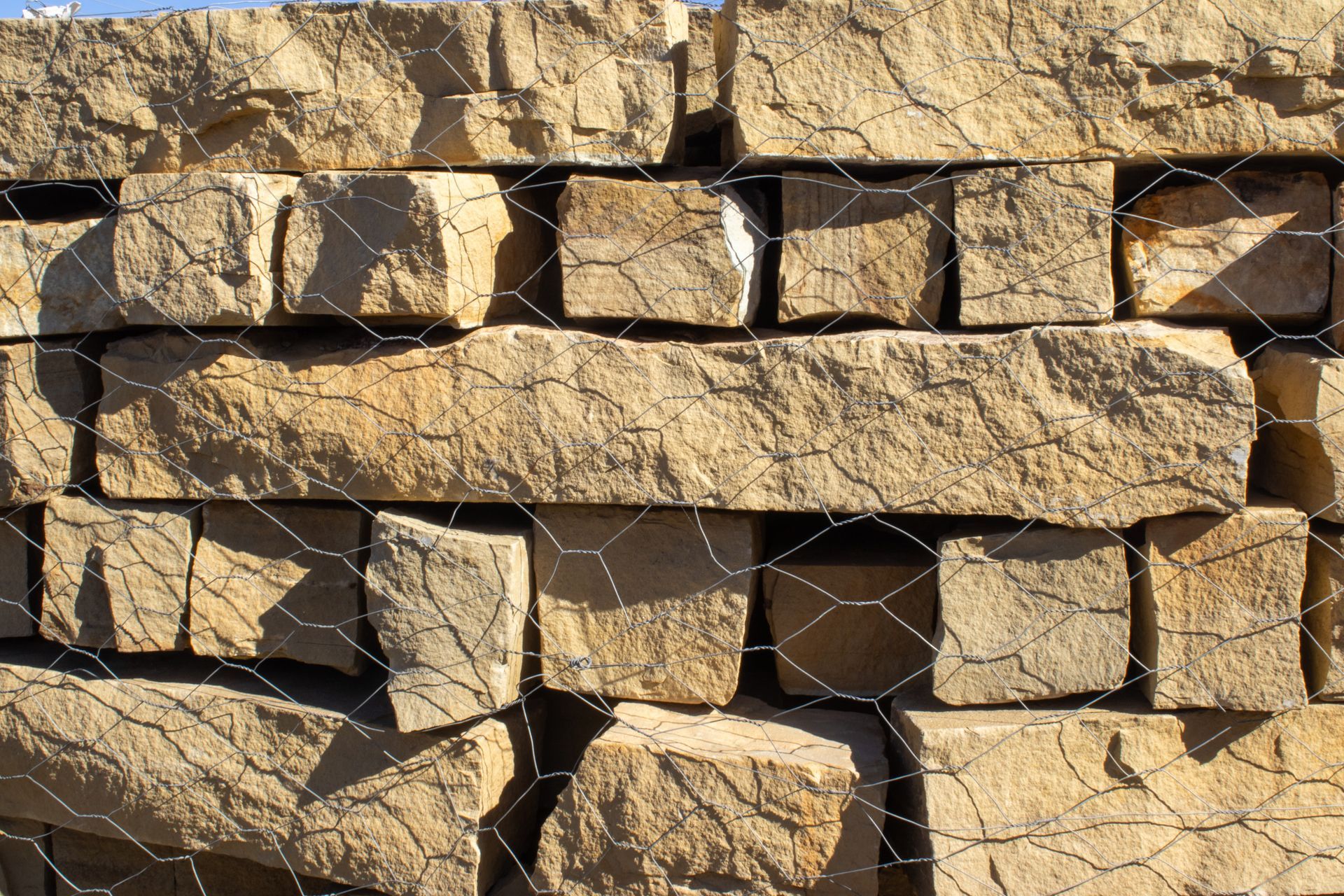 A stack of bricks behind a wire fence.