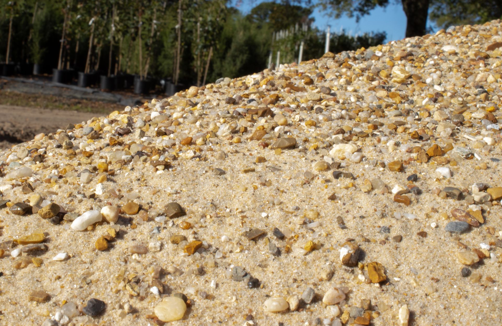A pile of sand and rocks with trees in the background