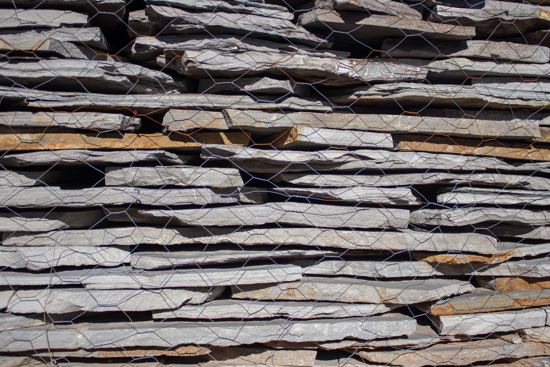 A pile of rocks stacked on top of each other behind a chain link fence.