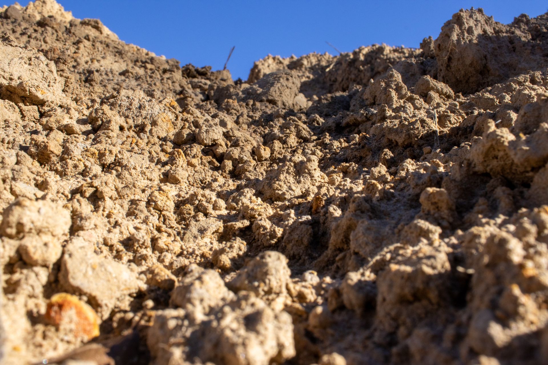 A pile of dirt and rocks in the desert with a blue sky in the background.