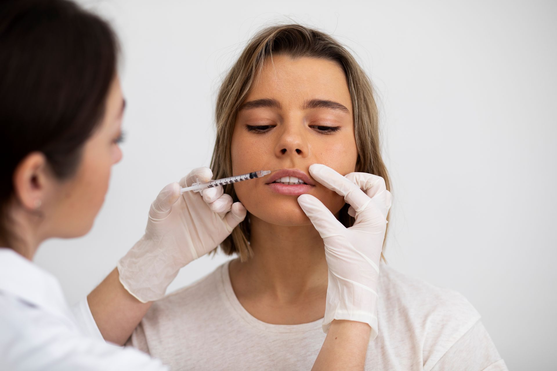 A woman is getting a botox injection in her lips.